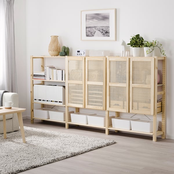 IVAR-Aufbewahrungsschrank mit Holz- und Bambustüren, geräumigen Regalen und verschiedenen Gegenständen. Hoch, neben einer großen Pflanze und unter einem Kunstwerk.