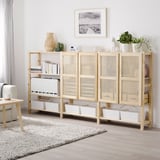 IVAR-Aufbewahrungsschrank mit Holz- und Bambustüren, geräumigen Regalen und verschiedenen Gegenständen. Hoch, neben einer großen Pflanze und unter einem Kunstwerk.