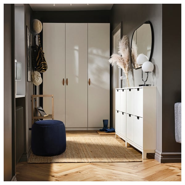 Moderner Eingangsbereich mit cremefarbenem Kleiderschrank, weißem Schuhschrank, blauem JÄRRESTAD-Hocker, Holzstuhl und dekoriertem Regal.
