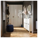 Moderner Eingangsbereich mit cremefarbenem Kleiderschrank, weißem Schuhschrank, blauem JÄRRESTAD-Hocker, Holzstuhl und dekoriertem Regal.
