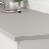 Küchenarbeitsplatte aus grauem Laminat, leicht zu reinigen und zu pflegen. Darunter sind Stützen sichtbar.