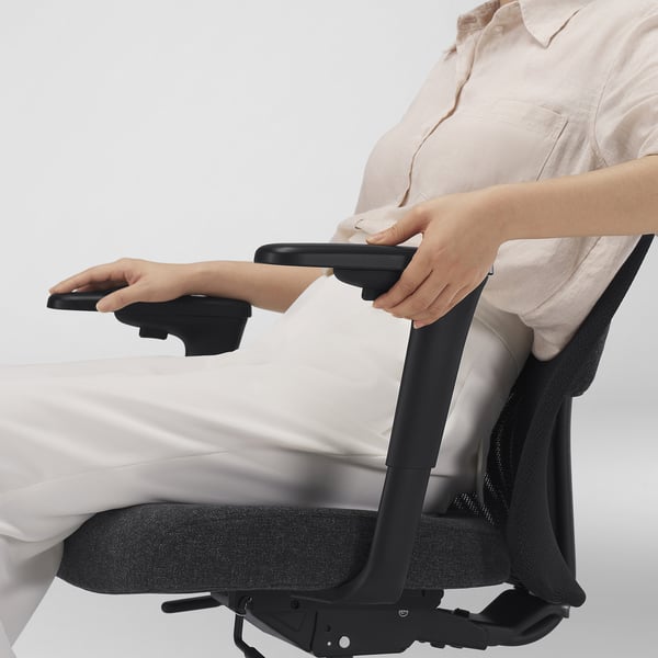 Person stellt die Armlehnen des Stuhls ein. Ergonomischer Bürostuhl mit verstellbaren Armlehnen und Lendenwirbelstütze.