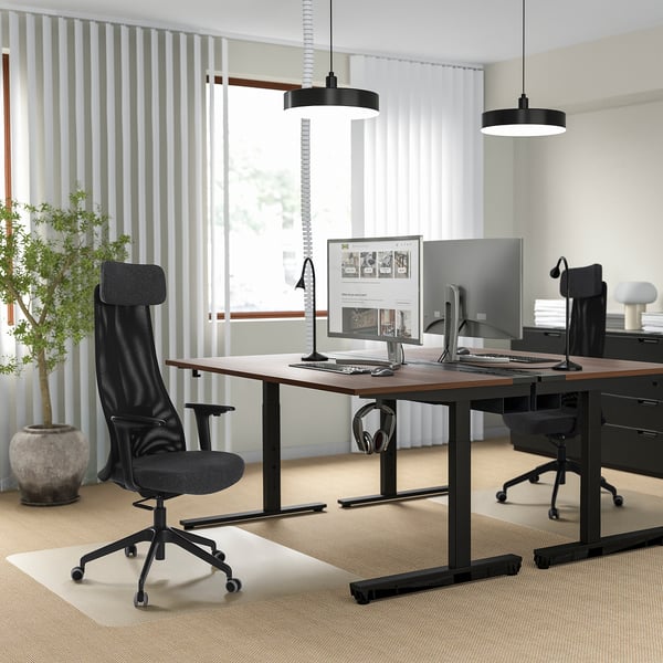Modernes Büro mit JÄRVFJÄLLET-Stühlen und verstellbaren Schreibtischen, Doppelmonitoren, Pendelleuchten, Jalousien, Pflanze.