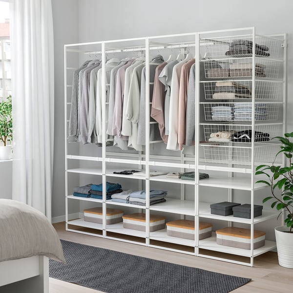 Weißer Metallschrank mit Regalen und Hängefläche, ordentlich organisiert neben einem Bett.