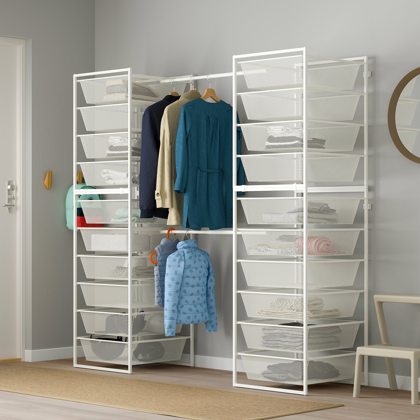 Weißer JONAXEL-Kleiderschrank mit Netzböden, Kleiderstangen und blauer Jacke. Inklusive Spiegel, Haken und Stuhl.