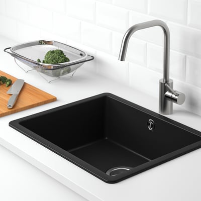 Moderne Küchenspüle mit Edelstahlarmatur, schwarzem Quarzmaterial und Sieb mit Brokkoli.