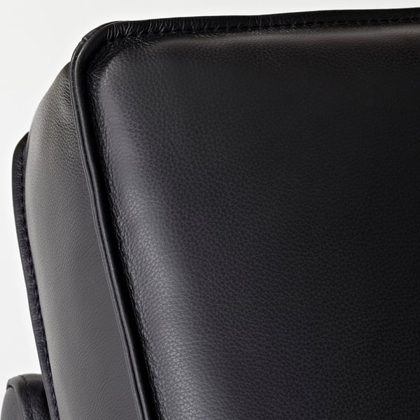 Nahaufnahme eines schwarzen Ledersofas, glatte Textur, fein genähte Kante, die auf hochwertige Verarbeitung hinweist.