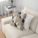 Beigefarbenes Sofa mit geometrischen Kissen auf einer gemütlichen Wohnzimmeranordnung.