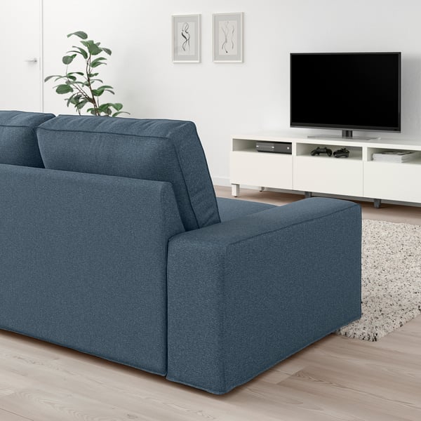Modernes Wohnzimmer mit großem blauem KIVIK-Sofa, elegantem TV-Ständer und stilvoller Einrichtung.