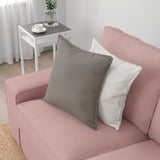 Ein rosafarbenes Sofa mit grauen und weißen Kissen, das seine geräumigen und bequemen Sitzgelegenheiten zur Schau stellt, perfekt zum Entspannen.