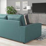 Modernes Wohnzimmer mit KIVIK Teal Sofa, zwei Kissen, Pflanze, TV, Gemälden.