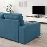 Modernes Wohnzimmer mit blauem KIVIK-Sofa, Flachbildfernseher und Pflanze.