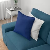 Blaugrünes Sofa mit Kissen. Der Beistelltisch verfügt über ein Teeservice und eine Vase.
