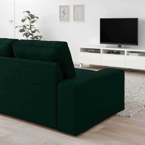 Modernes Wohnzimmer mit großem grünem KIVIK-Sofa, weißem TV-Ständer und Wandkunst.