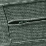 Nahaufnahme aus grauem gewebtem Textil mit teilweiser Reißverschlusstasche, die die hochwertige Verarbeitung zeigt.