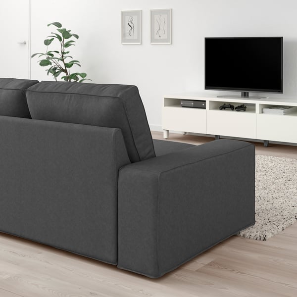 Graues KIVIK Sofa, Fernseher, Pflanze im modernen Wohnzimmer. Holzboden, weiße Wände, abstrakte Kunst. Gemütlich, minimalistisch.