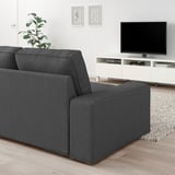 Graues KIVIK Sofa, Fernseher, Pflanze im modernen Wohnzimmer. Holzboden, weiße Wände, abstrakte Kunst. Gemütlich, minimalistisch.