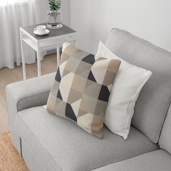 Graues Sofa mit karierten und weißen Kissen, Beistelltisch aus Holz mit Teeservice und Pflanze.