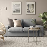 Modernes Wohnzimmer mit grauem KIVIK-Sofa, Naturdrucken, Beistelltisch und Pflanze.