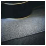 Nahaufnahme der KIVIK-Sofas aus strukturiertem grauem Stoff und schlanker schwarzer Kante.
