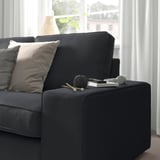 Modernes Wohnzimmer mit KIVIK-Sofa, Kissen, Fenster, Stricken, Garn, Fernbedienung, Buch.