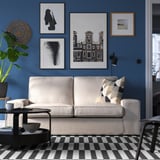 Modernes Wohnzimmer mit KIVIK-Sofa, kariertem Teppich, blauen Wänden und Wandkunst.