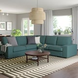 Teal KIVIK Sektionssofa mit modernem Design, groß und bequem, umgeben von gestreiftem Teppich, Couchtisch aus Holz und Hängelampe.