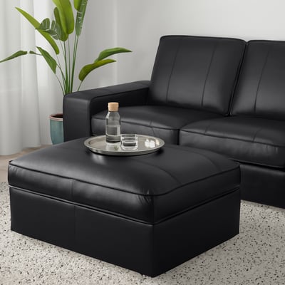 Modernes Wohnzimmer mit KIVIK Sofa, Fußhocker als Tisch, Pflanze.