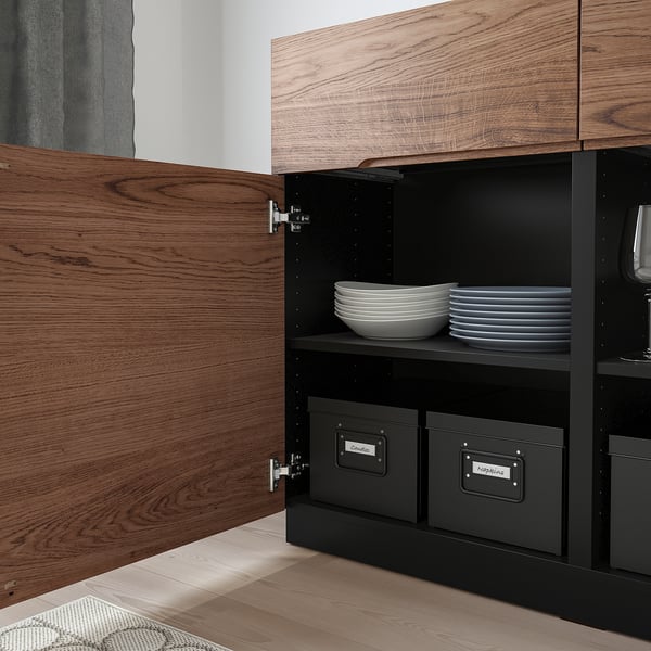 Sideboard aus Holz mit offener Tür, die den Blick auf gestapelte Teller freigibt. Integrierte Griffe, Eichenfurnier und organisierte Staufächer.
