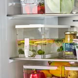 Offener Kühlschrank mit KLIPPKAKTUS-Behälter gefüllt mit Wasser, Fruchtscheiben und Eiswürfeln, bereit für die Ausgabe von gekühlten Getränken.