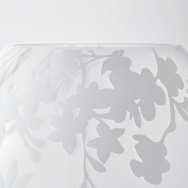 Weißer Glastisch mit geätztem Kirschblüten-Design, das weiches Licht reflektiert.