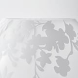Weißer Glastisch mit geätztem Kirschblüten-Design, das weiches Licht reflektiert.