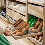 Organisierter Holzschrank mit beigem ausziehbarem Tablett für beige High Heels. Im Inneren befindet sich ein grüner Schuhteiler.