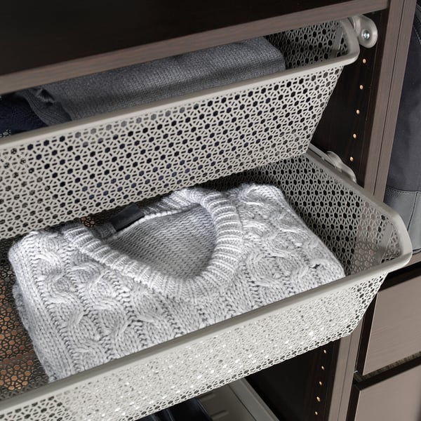 Metallgitterkorb, der den gefalteten Pullover im Schrank für die Luftzirkulation hält.
