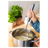 Person zerdrückt Kartoffeln mit einem Metallstampfer. Der lange Griff sorgt für den Griff in tiefe Töpfe.
