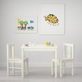 Kinderspielbereich mit weißem Tisch und Stühlen, bunten Tassen und Kunst zum Thema Käfer.