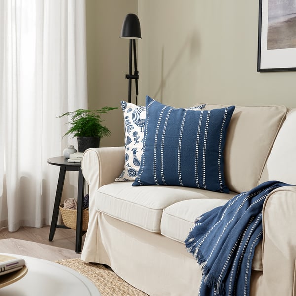 Beigefarbenes Sofa mit blau gestreiftem KRUTBRÄNNARE Kissen.