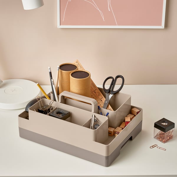 Schreibtisch-Organizer mit Schere, Stiften, Taschenrechner und Papier. Mehrere Fächer und ein Griff zum Tragen.