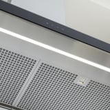 Moderne Dunstabzugshaube aus Edelstahl mit schlanken Touch-Bedienelementen und heller LED-Beleuchtung.