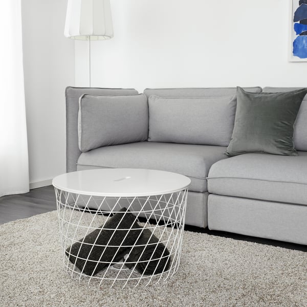 Modernes Wohnzimmer mit grauem Sofa, weißem KVISTBRO-Tisch und schwarzer Decke.