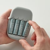 Hände halten ein graues Akkugehäuse mit vier LADDA 2450-mAh-Batterien, die zeigen, wie Batterien eingelegt oder entnommen werden.