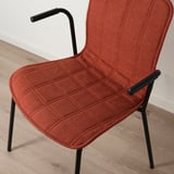 Leuchtend orangefarbener Polsterstuhl mit geschwungener Rückenlehne und Armlehnen auf schwarzen Metallbeinen.