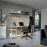 Home-Office-Einrichtung mit einem großen LAGKAPTEN-Schreibtisch mit schwarzem Stuhl, minimalistischem Dekor und wandmontierten Regalen, ideal zum Arbeiten und Entspannen.