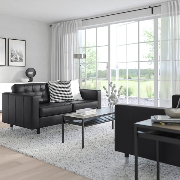 Modernes Wohnzimmer mit großem Fenster und schwarzem LANDSKRONA-Stuhl, elegantem Couchtisch, stilvoller Einrichtung, geräumig und hell.
