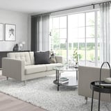 Modernes Wohnzimmer: weißes Sofa, Glastisch, gesprenkelter Teppich, Fenster mit Aussicht, minimalistische Einrichtung.