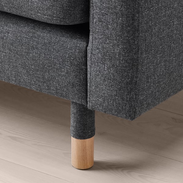Nahaufnahme eines modernen Sofabeins aus Holz und Stoff auf einem Holzboden.