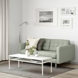 Modernes Wohnzimmer mit LANDSKRONA-Sofa, Couchtisch, grauem Teppich und Wandkunst. Gestylt mit Kissen, Vase und Ästen.