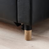 Dunkelgraues Sofa mit Holzbeinen, mit Glattleder bezogen, auf einem Holzboden platziert. Setzt auf Qualität und Design.