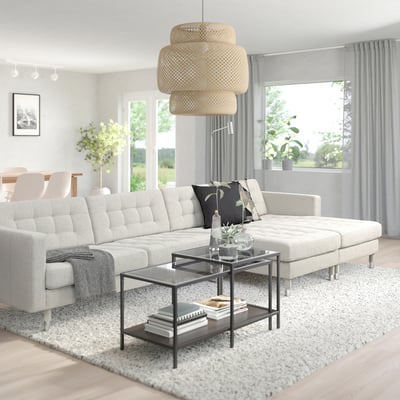 Modernes Wohnzimmer mit großem, l-förmigem, cremefarbenem LANDSKRONA-Sofa, Couchtisch aus Glas, Pendelleuchte aus Korbgeflecht und großen Fenstern mit Vorhängen.