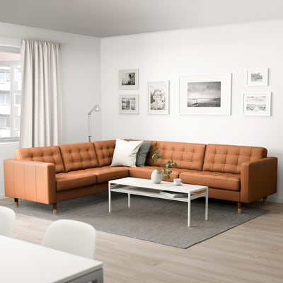 Modernes Wohnzimmer mit L-förmigem Sofa, weißem Stuhl, Couchtisch und Wandkunst. Minimalistisches Design.